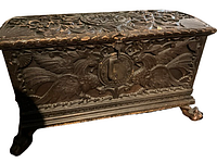 Angled front view of the carved pine chest showing top, front panel, and left claw foot