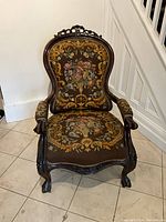 Front view of mahogany armchair showing carved crest, curved back and tapestry upholstery