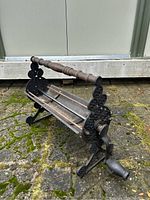 Side view showing ornate cast iron circular detailing and wooden turned handle.
