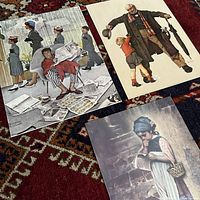 Three vintage art prints laid out on carpet: left showing detail of man in pajamas reading newspaper with others walking by (Big Moment), middle right print of older man and boy with umbrella (Sunday Morning), bottom right print of young girl reading book near brick wall (Before School).
