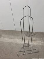 Chrome hanger stacker front full view showing vertical tubular metal frame with two rounded supports and triangular base.