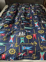 Full view of twin size nautical themed quilted duvet insert with ship wheels, anchors, and flag print spread out showing pattern and design.