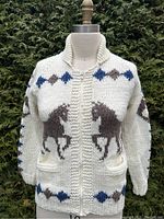 Front view of the cream curling sweater with horse pattern, displayed on a dress form with zipper closed.