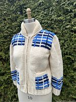 Front view of the vintage Mary Maxim chunky wool sweater with zipper closed, showing blue and navy plaid pattern across shoulders and cream body.