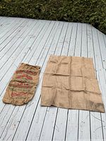 View of both burlap sacks placed on wooden deck, showing size difference between typical potato sack and extra large sack.