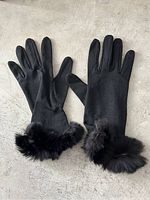 Pair of black leather gloves laid flat showing the outer side with fur trim at wrists.