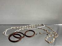 View of vintage white and cream beaded necklaces, three wooden bracelets, and small jewelry pieces