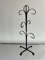 Full view of the vintage brown metal mug tree holder with six hooks and cross base.