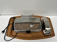 Waffle maker, stainless steel butter tray, and teak tray all placed on white background for clear view