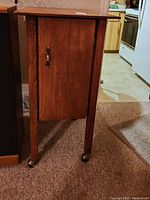 Front view of the oak cabinet showing the single door and caster wheels at the bottom.