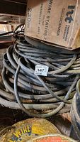 Coiled black electrical cables with a cardboard box on top labeled '230m chameleon grey' with MaxSold lot tag 347 attached