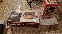 Photo showing the Canadian Camper Two Burner Propane Stove in its original box with price tag.
