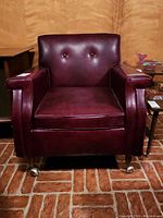 Front view of burgundy vinyl armchair on casters