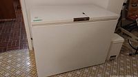 White Eaton Viking chest freezer with lock and key, closed lid, positioned on tiled floor.