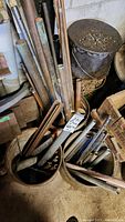 Four metal buckets filled with assorted metal pipes and heavy chains, showing rust and wear.