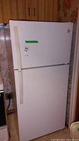 Full front view of white Kenmore refrigerator with top freezer and vertical door handles. Shows overall condition and design.