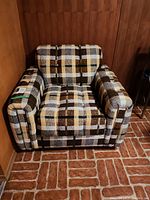 Front view of plaid upholstered armchair showing seat, arms and casters