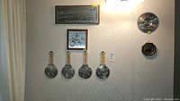 Wall display with three framed wall decor pieces with metal inserts and four rectangular pewter medallions below them