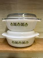 Stacked view of the two casserole dishes, with milk glass dish on bottom and clear glass dish on top, showing floral pattern and lids.