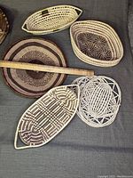 Overview of assorted woven wicker items on a grey fabric surface showing patterns and shapes