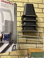 Photo showing packaging of Starfrit can crusher, stacked black bed risers, and white metal pop can dispenser on shelf.