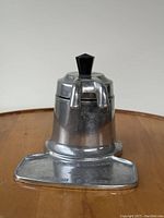 Full view of vintage aluminum espresso coffee maker showing the base, spout, and black bakelite knob on top.