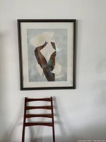 Framed print hanging above a wooden chair showing full artwork and frame.