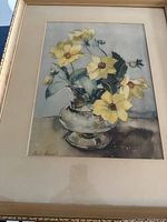 Front view of framed watercolor print showing yellow flowers in glass vase and visible water stain on lower mat.