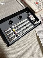 Set of four Koh-I-Noor Rapidograph pens in plastic case with ink bottle and caps visible.
