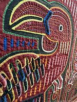 Close-up of detailed stitching and applique on one bird's head and wing with vivid colors and intricate fabric work