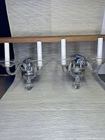 Pair of Bohemian glass and chrome 2-arm wall sconces shown from front on a light neutral background horizontally with wooden rod above.