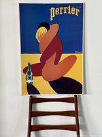 Full view of mounted Perrier poster on wall above chair
