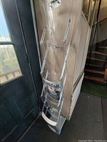 Folding magazine stand placed near door, showing its height and transparent compartments holding magazines.