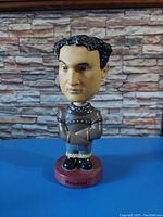 Front view of Harry Houdini bobblehead figurine with arms crossed in straitjacket and labeled base
