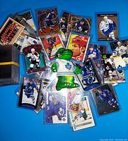 Hockey card collection laid out with individual cards in protective sleeves and a green alligator figurine in centere