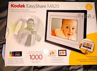 Box of Kodak EasyShare M820 digital photo frame showing product name, features, and image of the frame with baby photo.