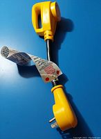 Yellow RV trailer generator plug with flexible cable and three-prong plugs on each end.