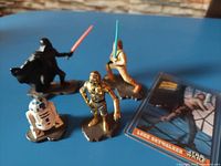 Four Star Wars die cast metal figures arranged on a blue surface alongside a Luke Skywalker character card.