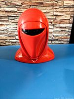 Front view of a red Imperial Guard helmet head with black visor, plastic toy playset head.