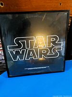 Front view of the framed Star Wars soundtrack LP showing the Star Wars logo and the black frame.