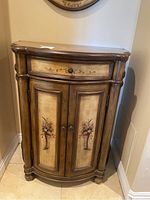 Front view of the wooden entry table showing drawer and floral painted cabinet doors.