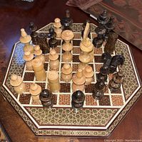 Top-down photo showing the octagonal inlaid chess board with assembled two-tone wooden chess pieces positioned for play.