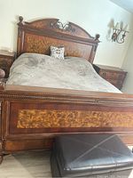 Front view of ornate wooden king bed frame with headboard, footboard, and side rails