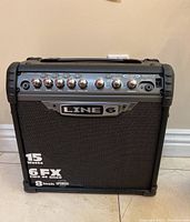Front view of Line 6 Spider III 15 guitar amp showing control panel, knobs, and speaker grill with Line 6 branding.
