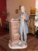Front angle of the porcelain attorney figurine on decorative table with opening filing cabinet drawer and book at base.