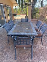 Photo showing the full patio table set on stamped concrete with six chairs around it.