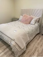 Queen bed with geometric upholstered headboard, nightstand on left, bedding included for display only