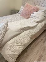 Queen bedding with patterned sheets, decorative coverlet and pillows including a pink furry pillow.