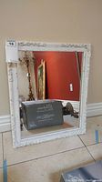 Front view of the white framed wall mirror showing the etched decorative details on the frame and good reflective glass surface.