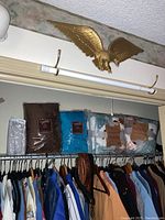 Photo showing four packaged blankets including three Berkshire decorative throws and one full/queen blanket or sheet set resting above a closet rod with clothing.